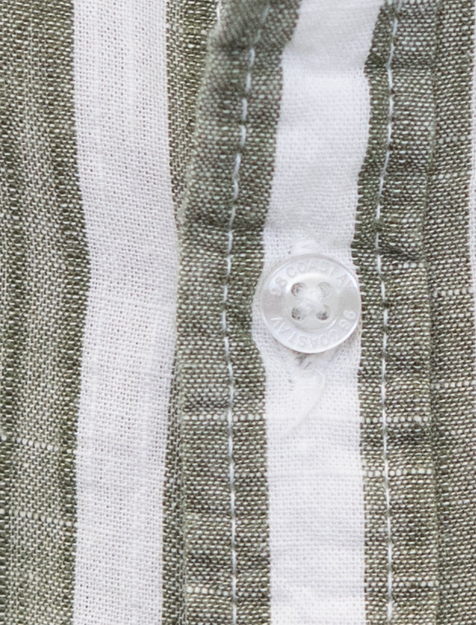 Detalle de la textura y botón en camisa rayada olivo para niño