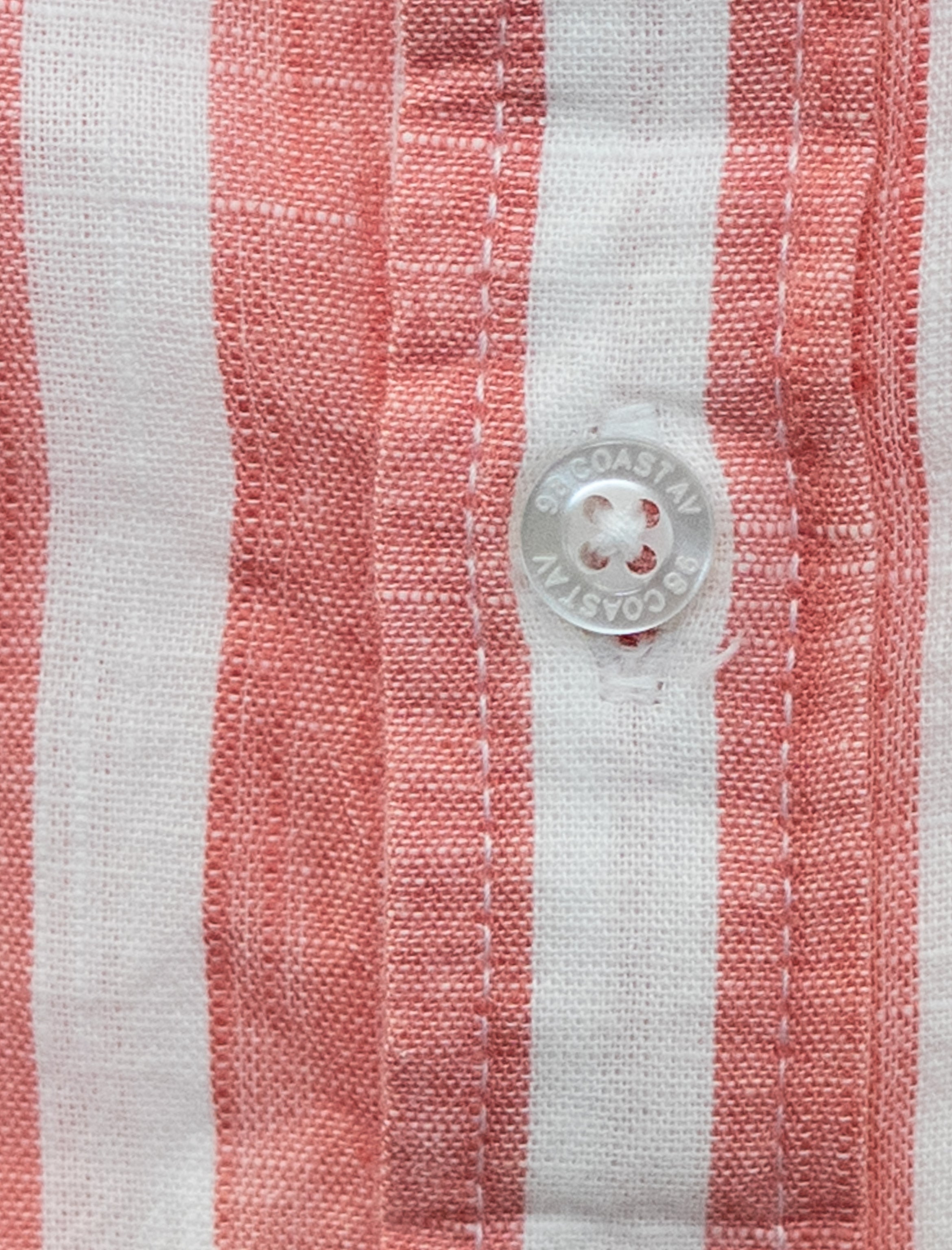 Detalle de textura y botón en camisa rayada rosa para niño