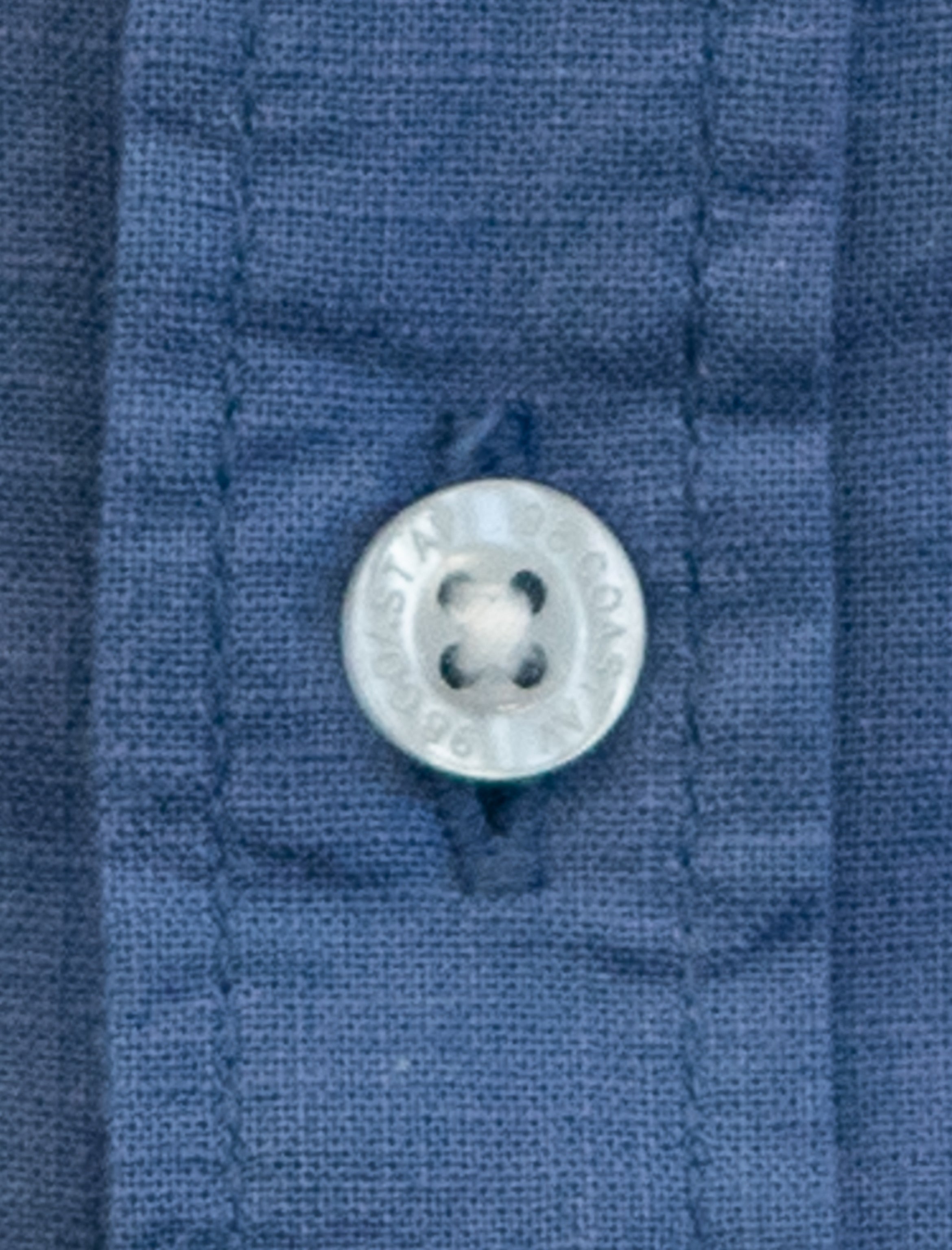Detalle de textura y botón en camisa infantil de algodón slub color azul