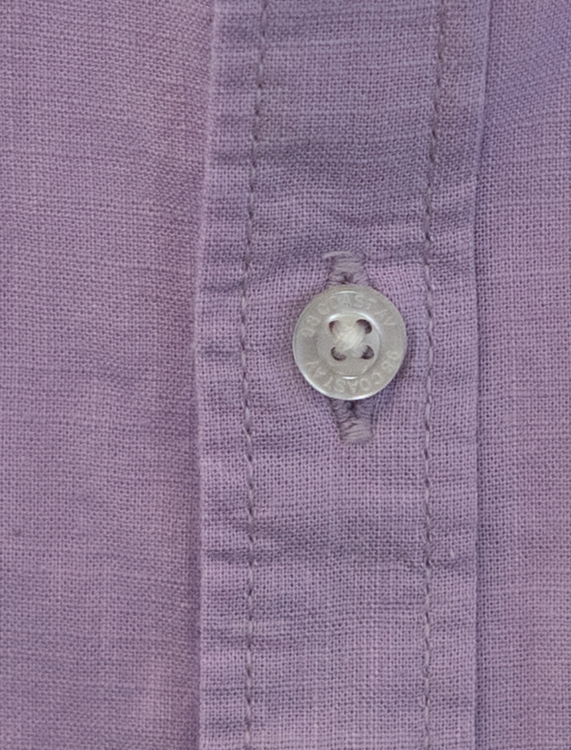 Detalle de textura y botón en camisa infantil de algodón slub color lila