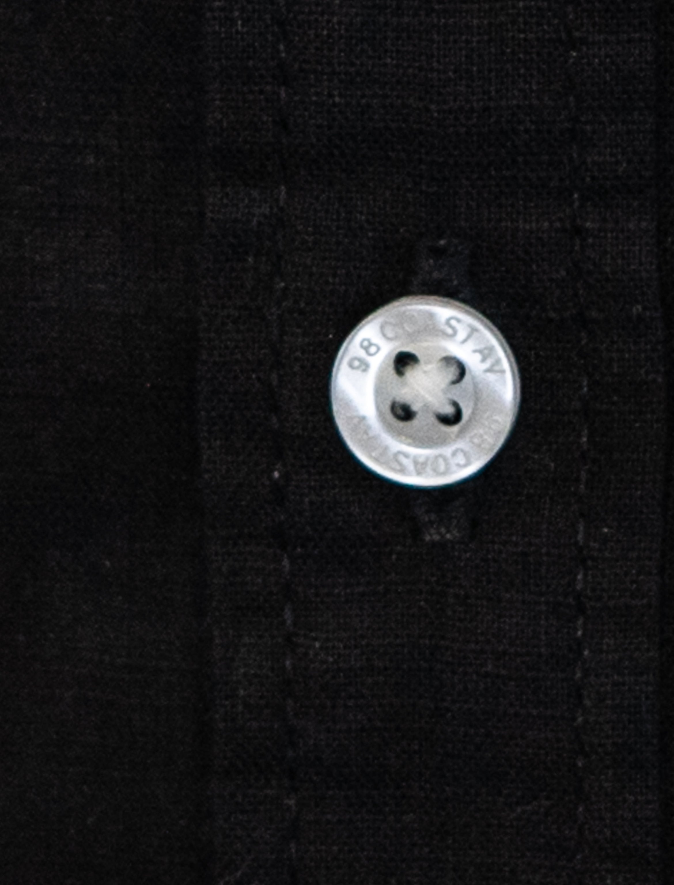 Detalle de textura y botón en camisa infantil de algodón slub color negro
