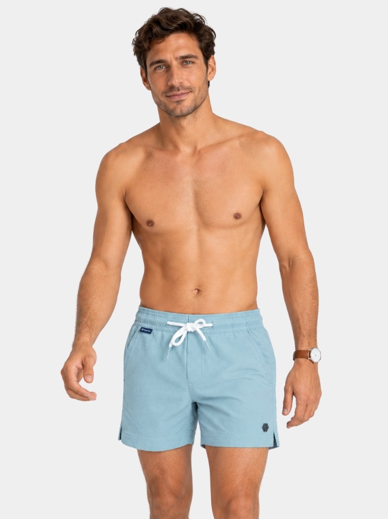 Short de baño Seersucker Capri azul claro para hombre, vista lateral con hexágono de logo metálico - 98 Coast Av