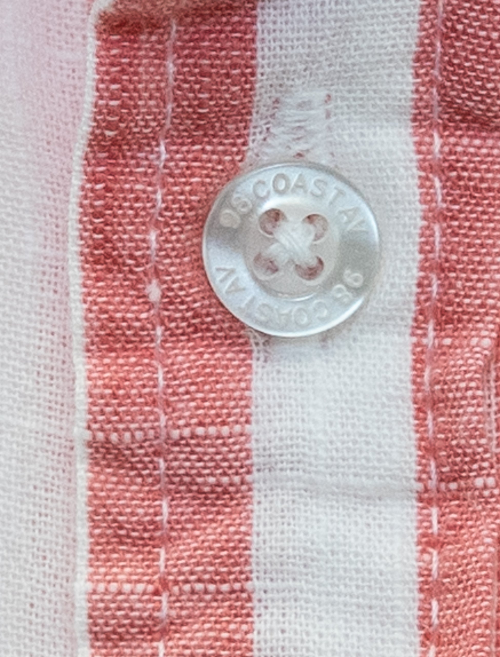 Detalle de la textura y botón en camisa rayada rosa para niño