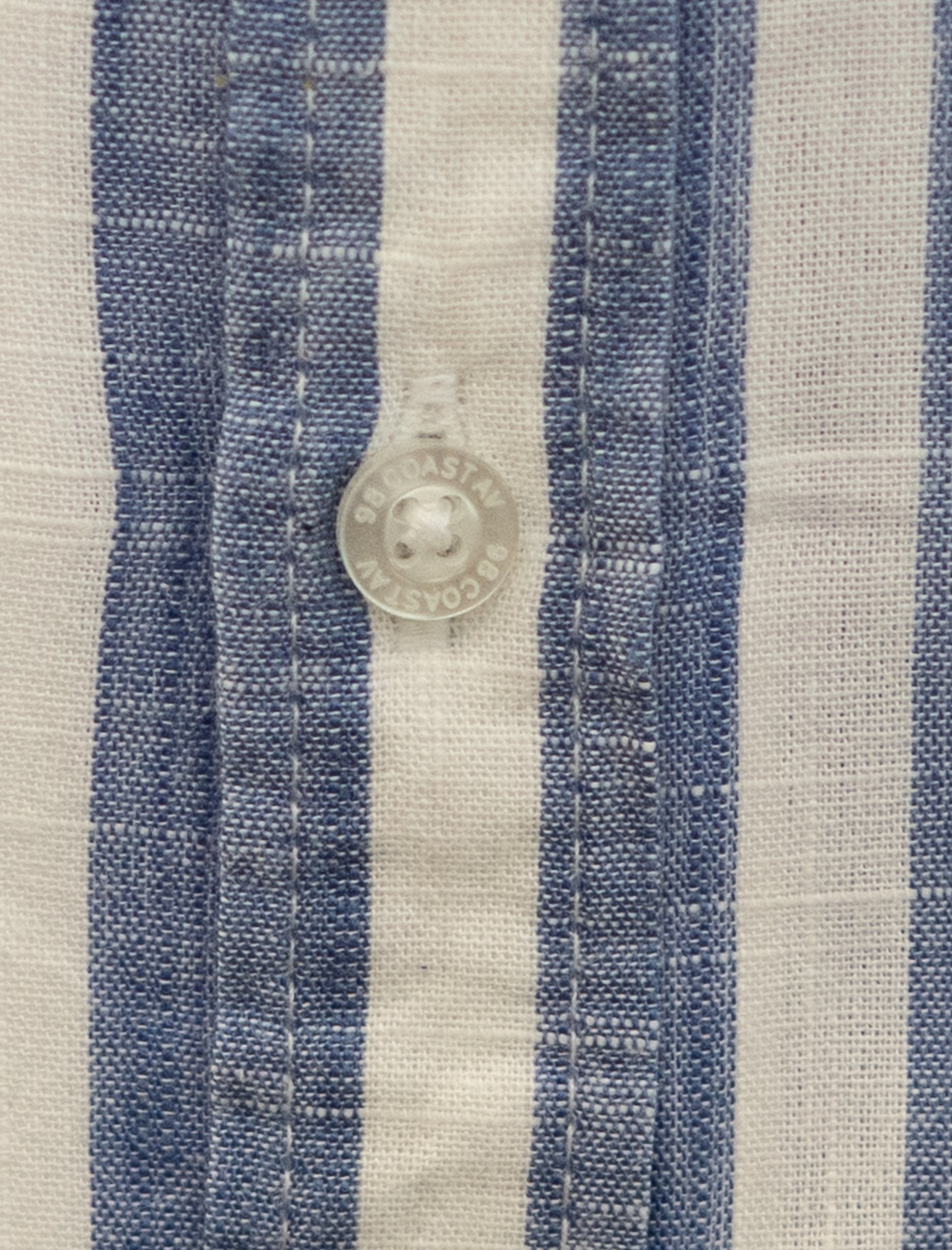 Detalle de textura y botón en camisa rayada azul para niño