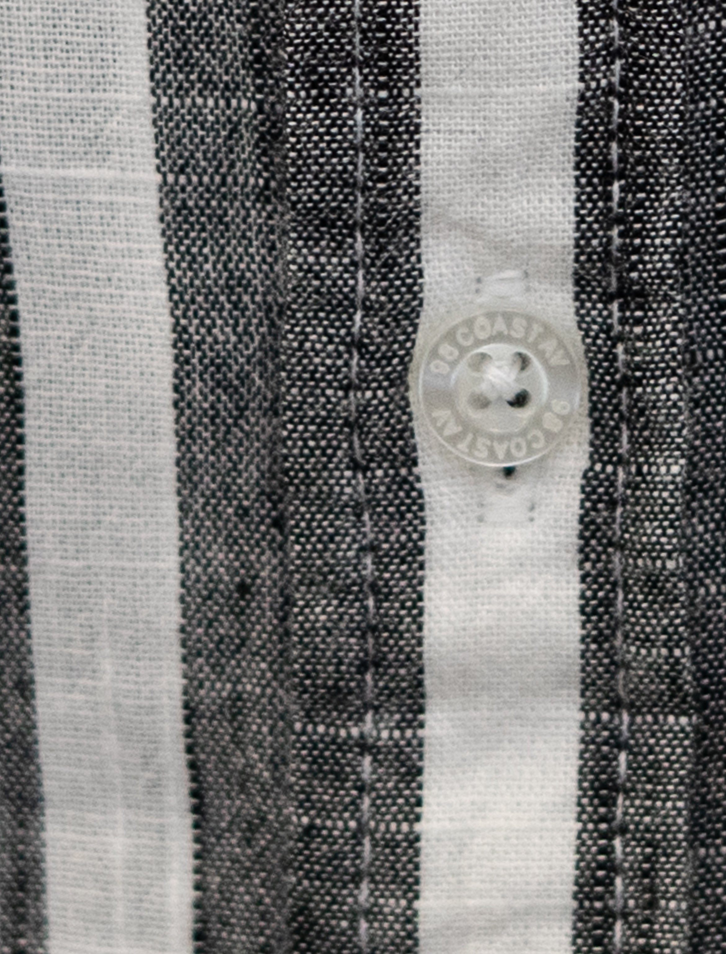 Detalle de textura y botón en camisa rayada negrapara niño