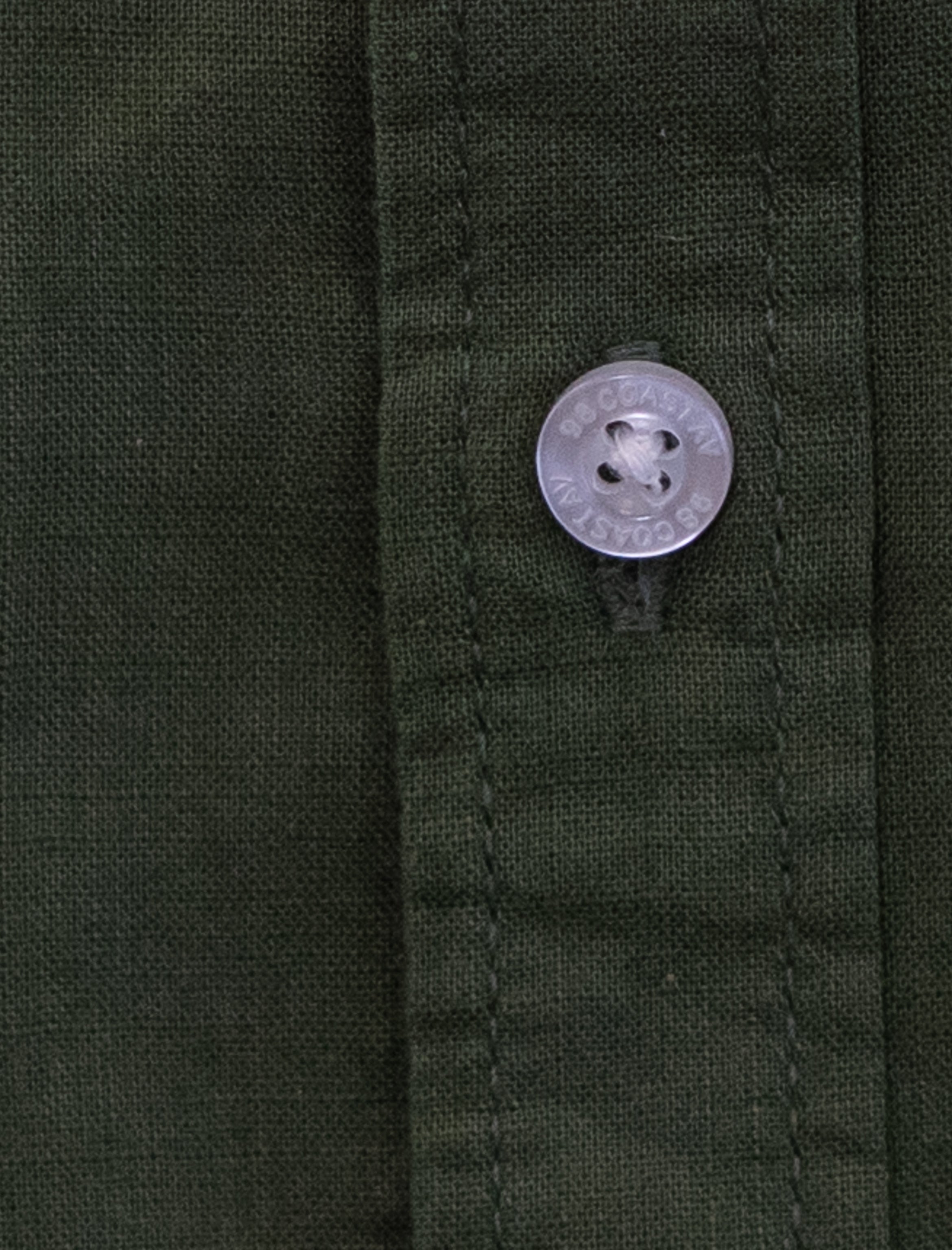 Detalle de textura y botón en camisa infantil de algodón slub color olivo